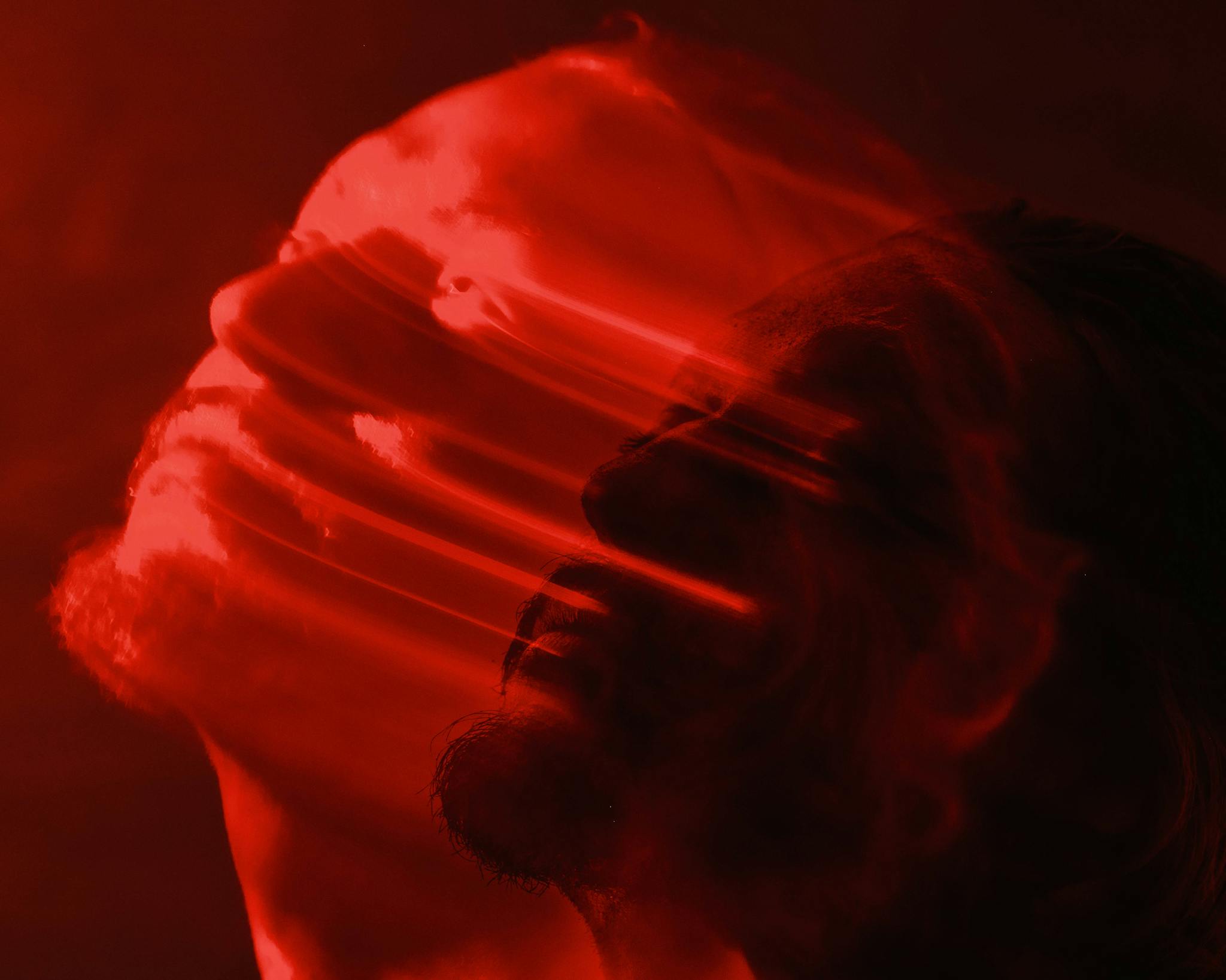 Artistic double exposure of a man with a red blurred motion effect, conveying emotion.